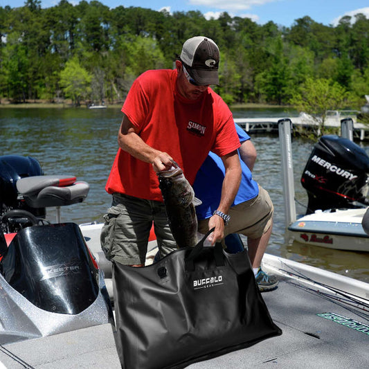 Two men on a boat with a black bag labeled 'Buffalo Outdoors' near a lake.