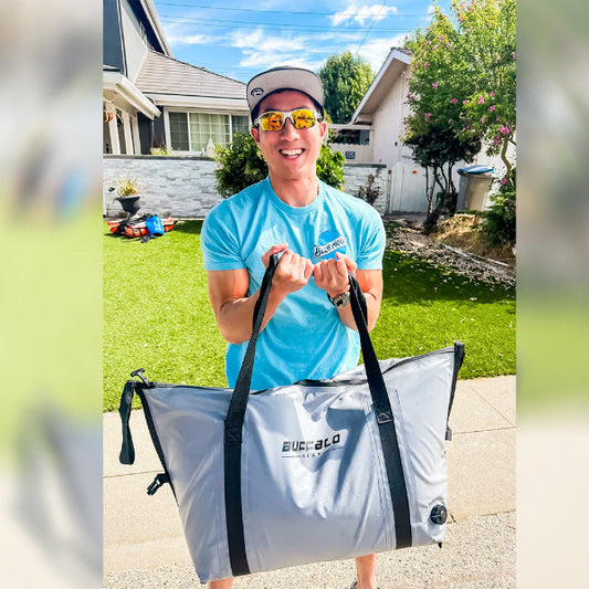 Person holding a large gray bag with branding in a residential area