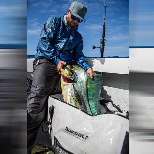 Man holding a large fish on a boat with a clear blue sky in the background