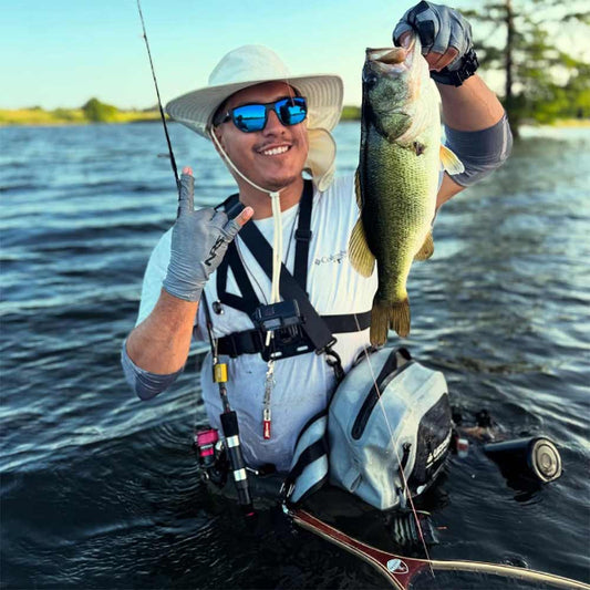 Fisher holding a large bass by a body of water
