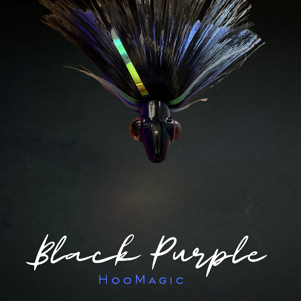 A fishing lure labeled 'Black Purple' by HooMagic, featuring a black and purple body with iridescent blue, green, and yellow accents on a dark background.