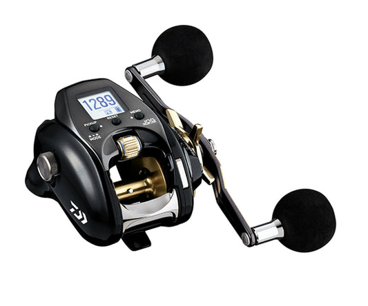 A Daiwa casting fishing reel with a black body, gold and silver metallic components, and black foam-wrapped handles, shown on a solid white background.