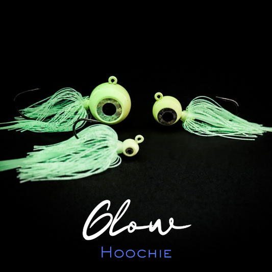 Three green fishing lures with tassels on a black background, labeled 'Glow Hoochie'.