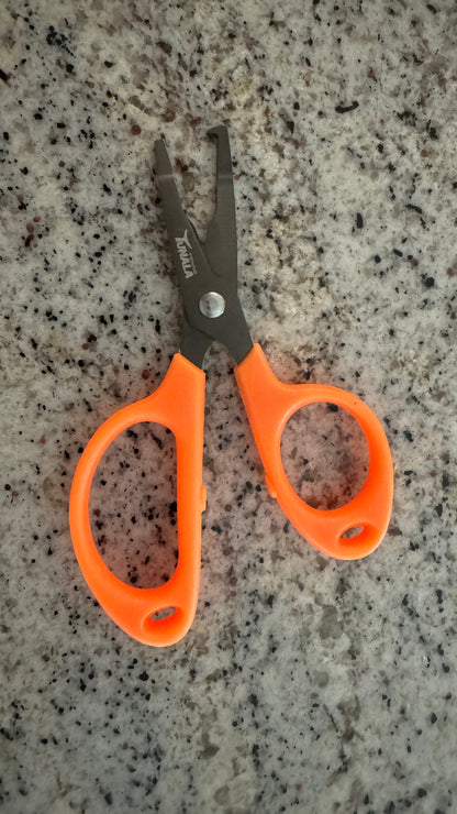 Orange-handled pet clipper scissors with dark gray metal blades, placed on a speckled granite countertop.
