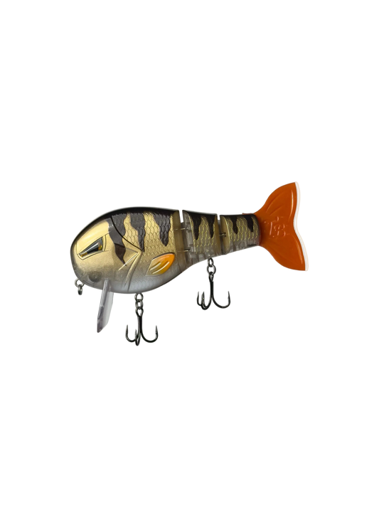 A soft plastic fishing lure shaped like a fish, featuring a gold and black tiger-stripe pattern on the top, a silver belly, and a bright orange tail, shown against a plain white background.