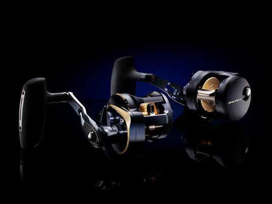 A high-end baitcasting fishing reel with a black handle and a metallic black body featuring gold accents, shown on a reflective black background with a blue glow.